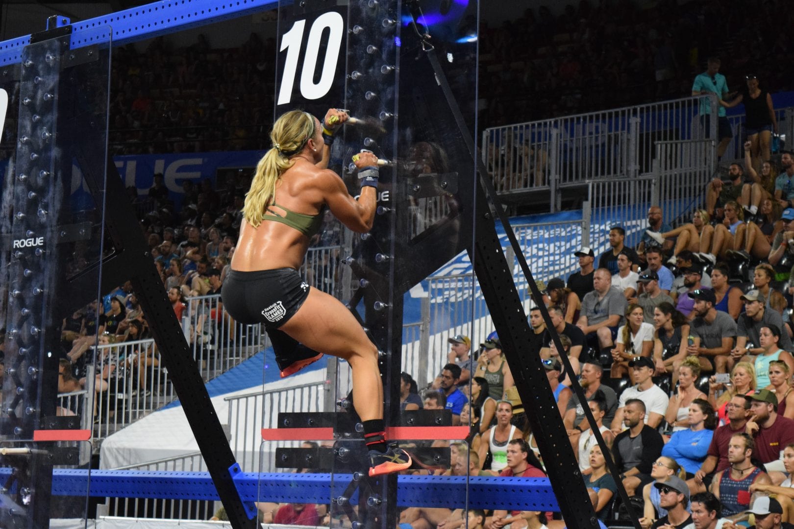 Amanda Barnhart climbs a pegboard in the Coliseum at the 2019 CrossFit Games