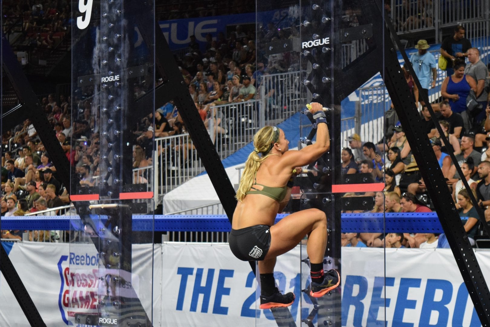 Amanda Barnhart climbs a pegboard in the Coliseum at the 2019 CrossFit Games