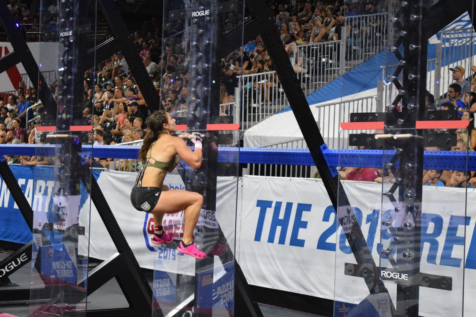 Bethany Shadburne climbs pegboards in the coliseum at the 2019 CrossFit Games.