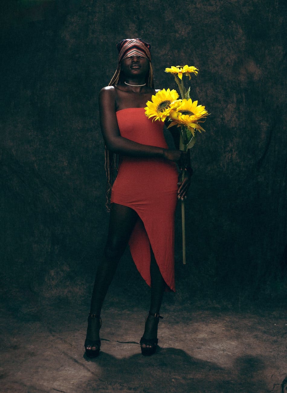 woman in red dress with high leg slit holding sunflowers